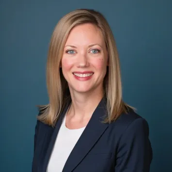 Professional woman with blonde hair smiling on blue background