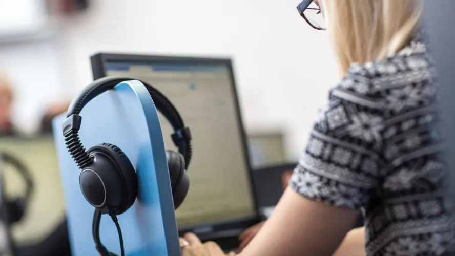Female interpreter at computer with headset 
