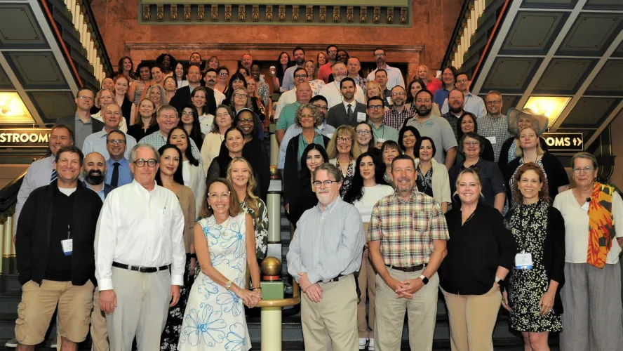 Group of diverse adults posing on decorative staircase indoors