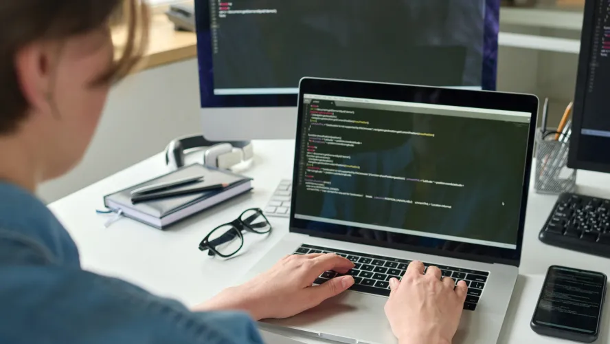 Woman typing on laptop and desktop computers