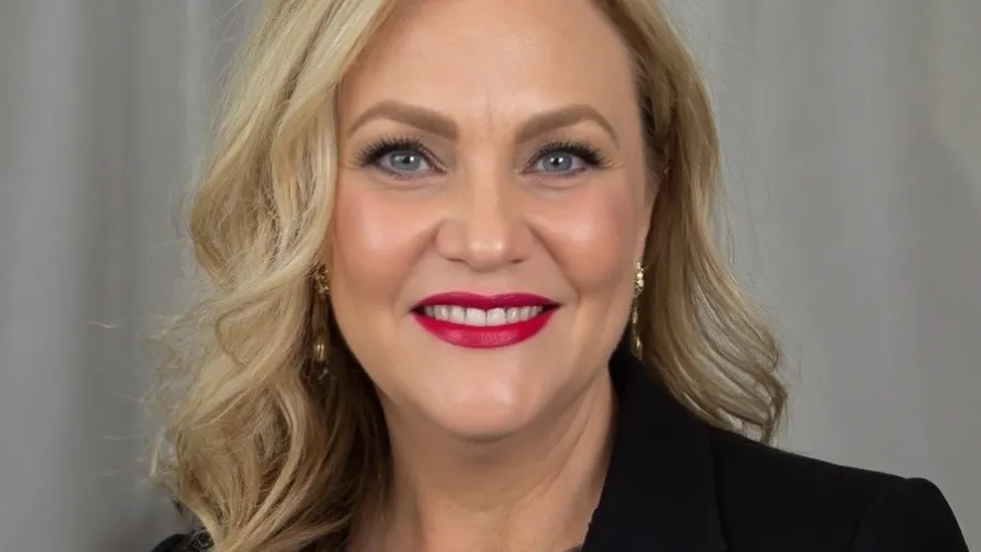 Professional woman with blonde hair, black blazer, smiling