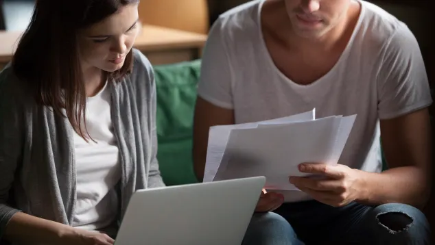 Two young adults reviewing documents and laptop together