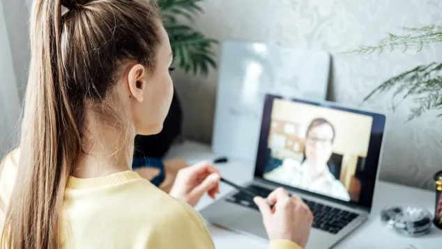 Woman attending virtual meeting on laptop at desk.