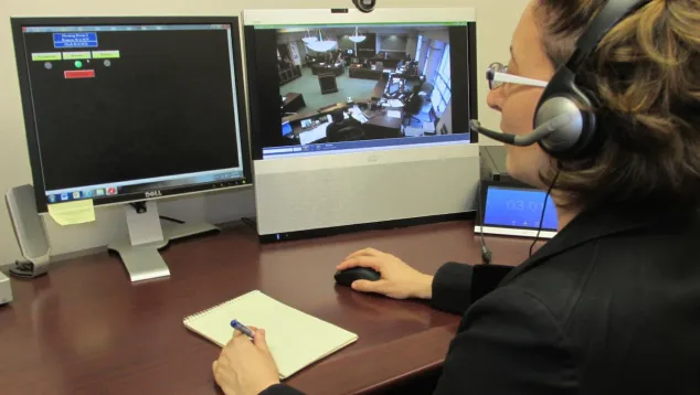 Courtroom video monitoring and note-taking by staff member.