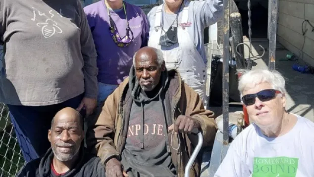 Group of diverse people gathered outside, smiling together.