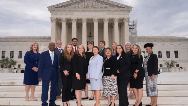 Group of diverse professionals standing on steps in front of courthouse