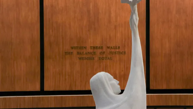 White statue of woman holding scales with justice quote