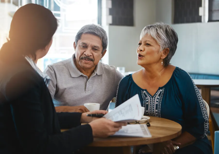 Older couple consulting with advisor at cafe table