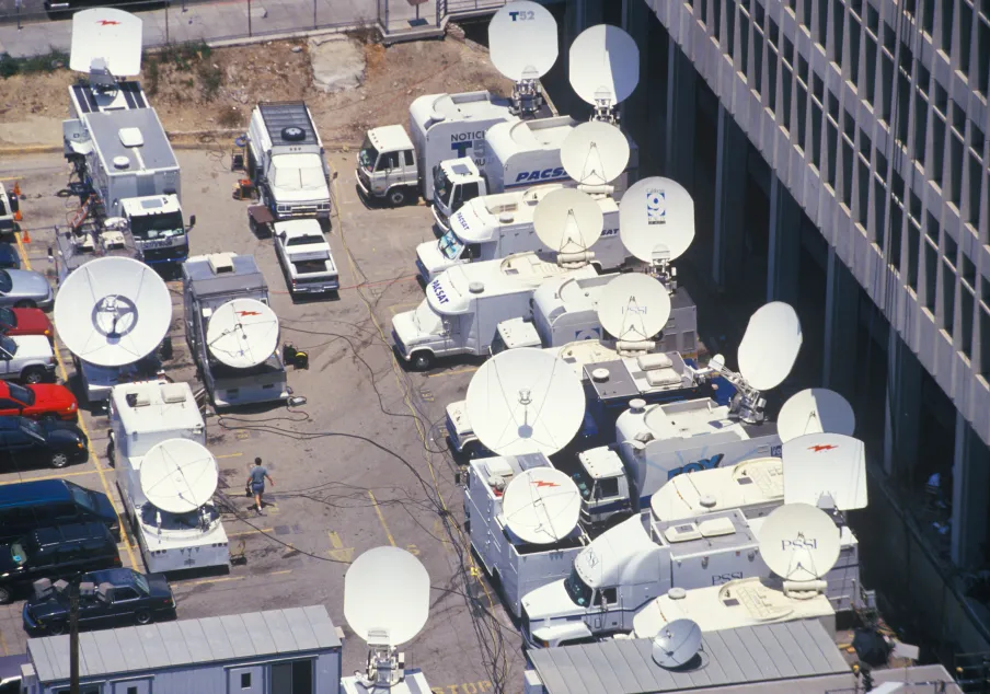 Satellite news trucks with large broadcasting dishes parked outdoors