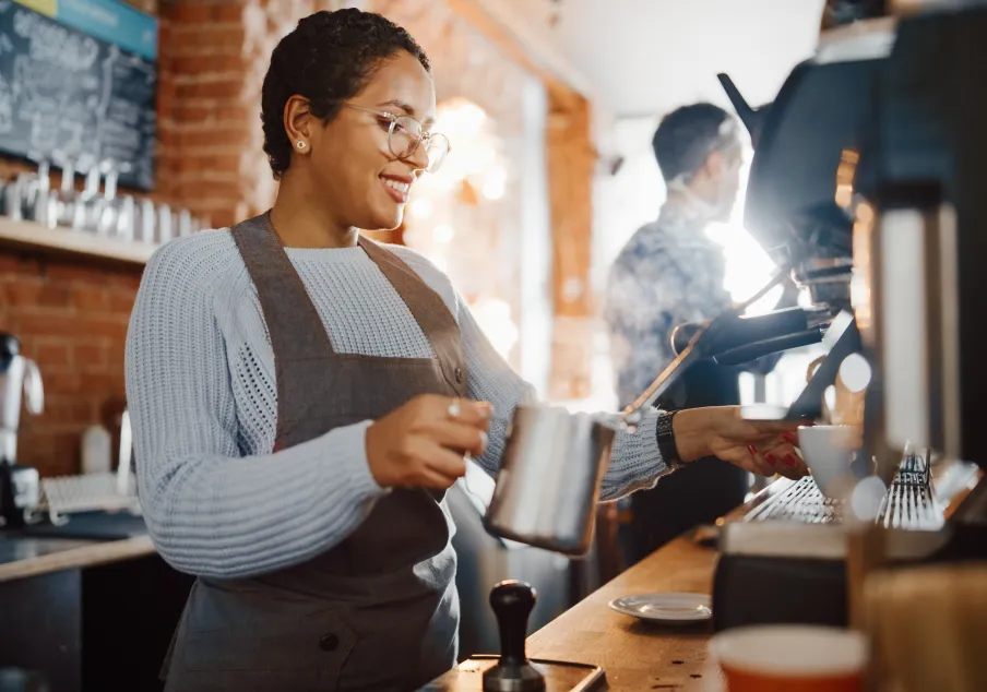 Barista steaming milk for coffee in cafe