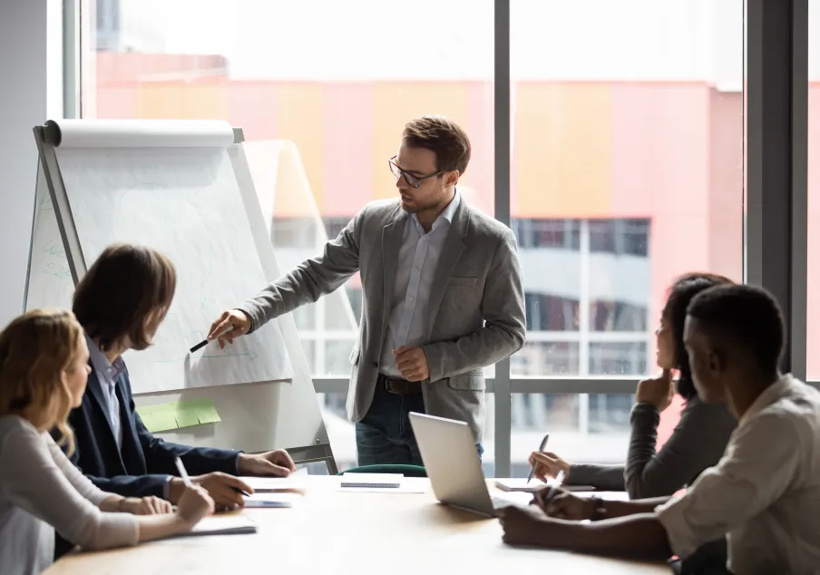 Man presenting to diverse group in a meeting room.