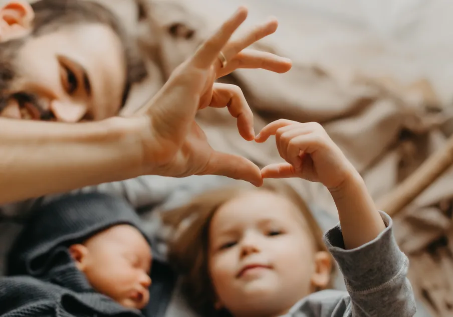 Adult and child forming heart shape with hands together