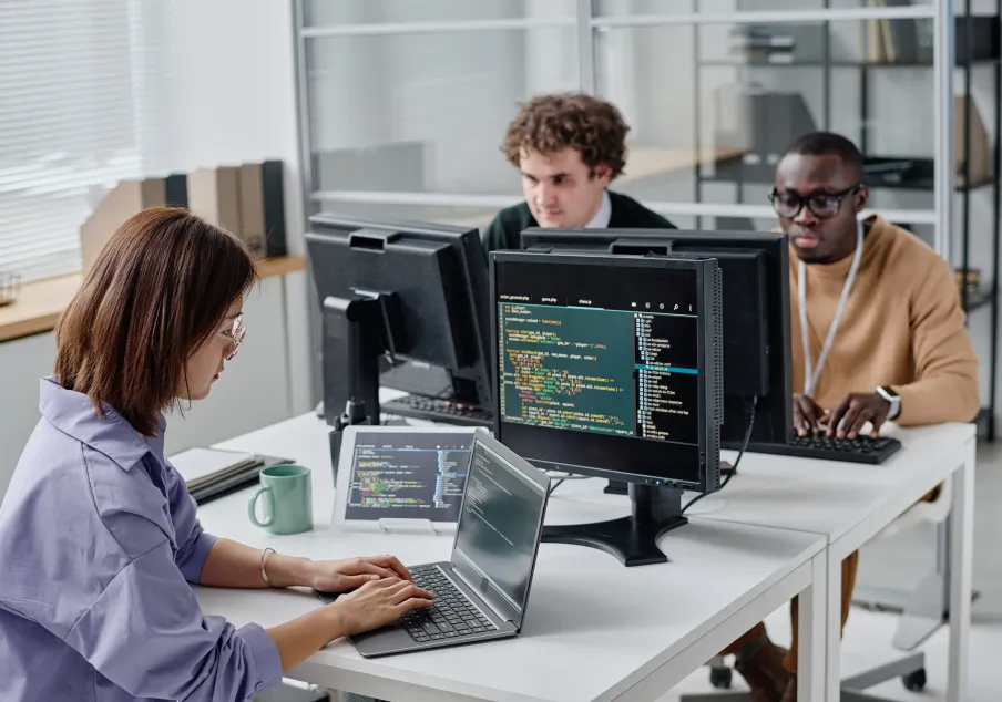 Two men and a woman working on computers in office
