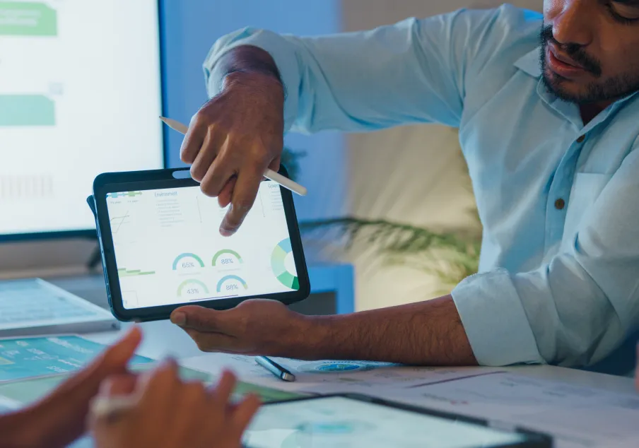 Man presenting data and charts on tablet during meeting