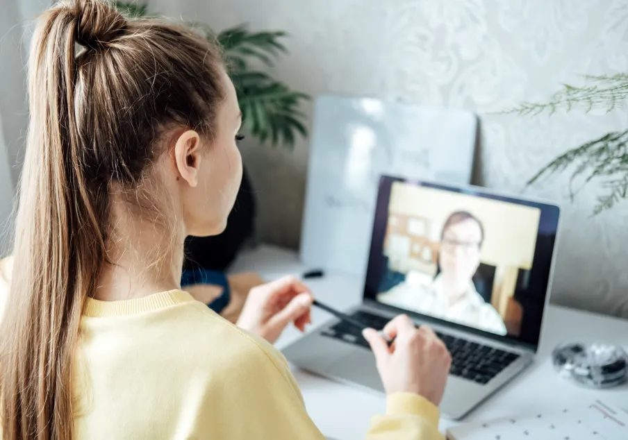 Woman attending virtual meeting on laptop at desk.