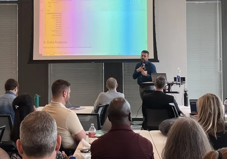 Presenter with microphone addressing seated audience in conference room