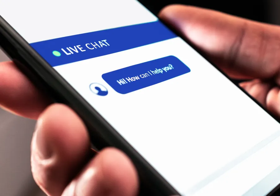A person holding a mobile device looking at a chatbot with a live chat feature.