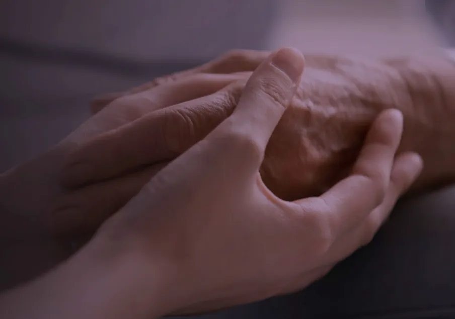 Younger hands gently holding older hands in support.