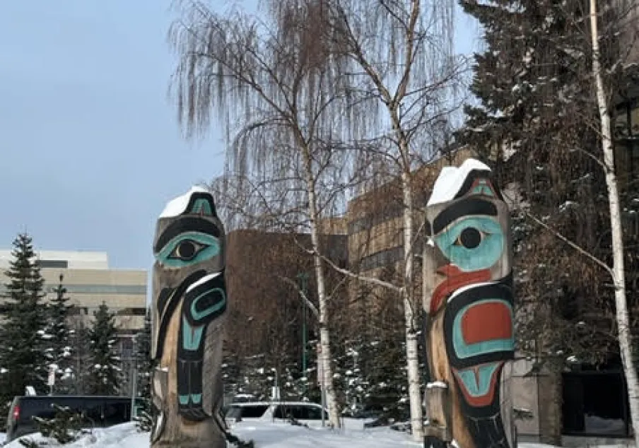 Two painted totem poles in snowy outdoor setting.