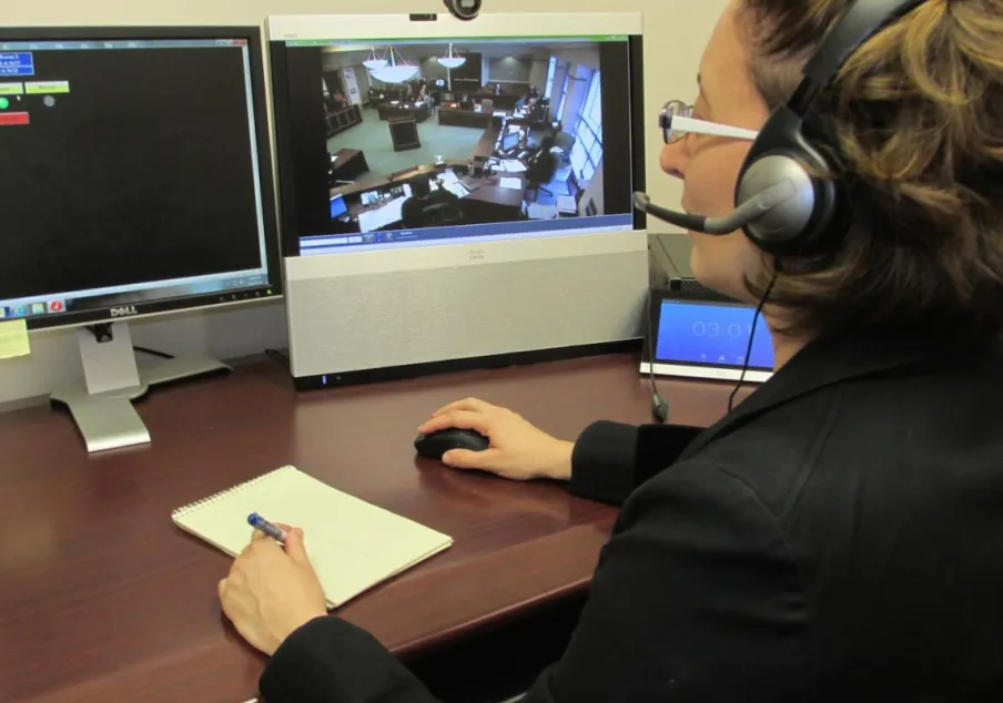 Courtroom video monitoring and note-taking by staff member.