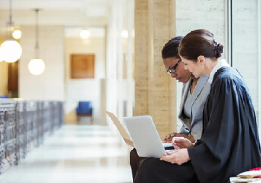 Two women reviewing laptop in courthouse hallway