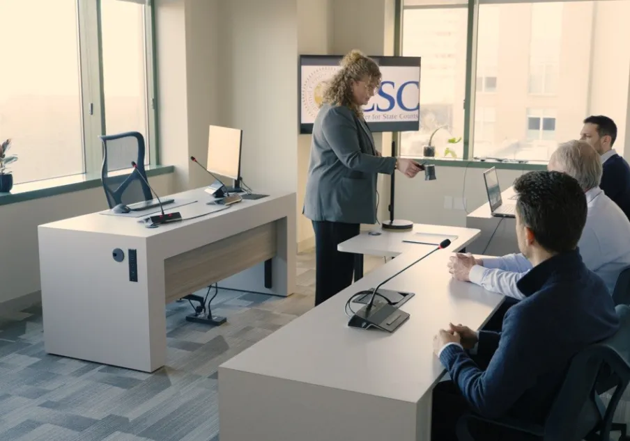Woman presenting to three men in a modern office courtroom setting