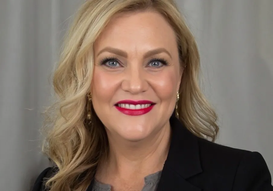 Professional woman with blonde hair, black blazer, smiling