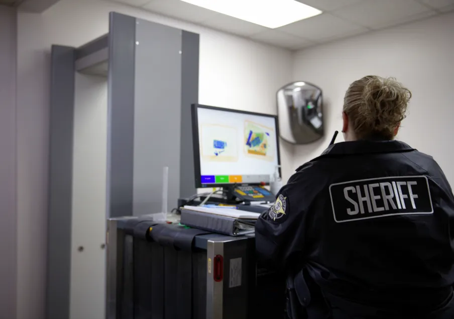 Sheriff officer monitoring security scanner at checkpoint