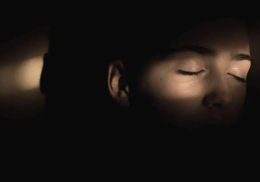 Partial face of person with closed eyes in shadow