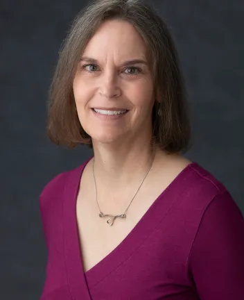 Portrait of woman in magenta top with gray background