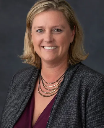 Professional headshot of smiling woman with necklace