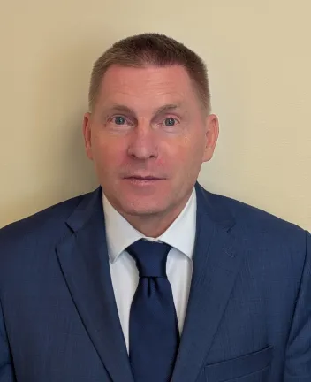 Man in blue suit and tie against beige wall