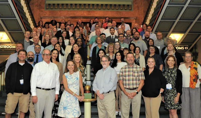 Group of diverse adults posing on decorative staircase indoors