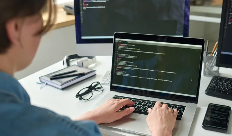 Woman typing on laptop and desktop computers