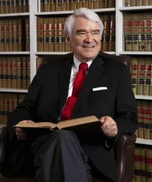 Smiling man in suit with book in law library