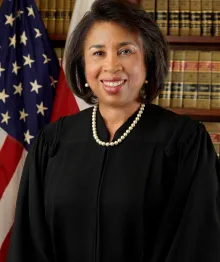 African American female judge in robe and pearls smiling