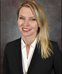 Professional woman smiling, wearing black blazer and white blouse